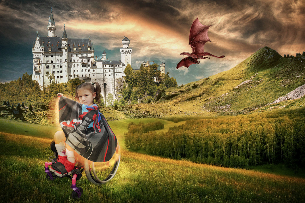 Young girl in a wheelchair wearing a superhero cape with a castle and dragon in the background.