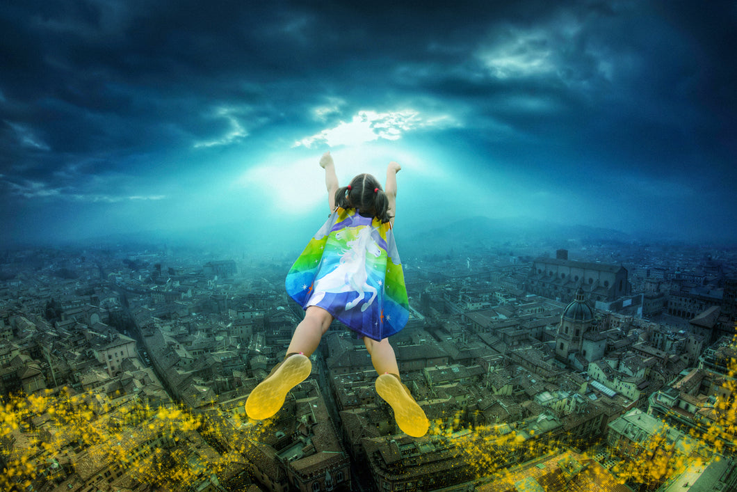 Girl flying over a city in a unicorn superhero cape.