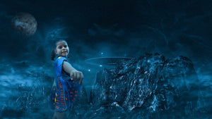 Young girl wearing a superhero cape and standing in a futuristic space landscape