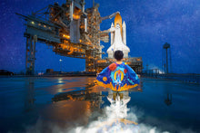 Load image into Gallery viewer, Young boy with a superhero cape standing in front of a space shuttle launch
